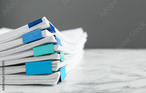 Stack of documents with binder clips on marble table against grey background, closeup. Space for text photo