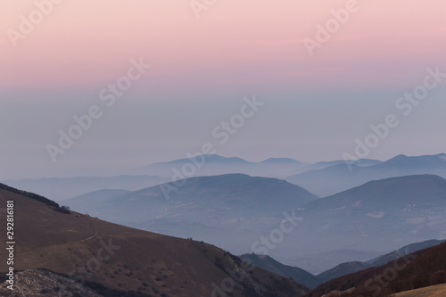Beautifully colored sky at dusk, with mountains layers and mist between them