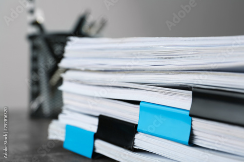 Stack of documents with binder clips on grey stone table  closeup view