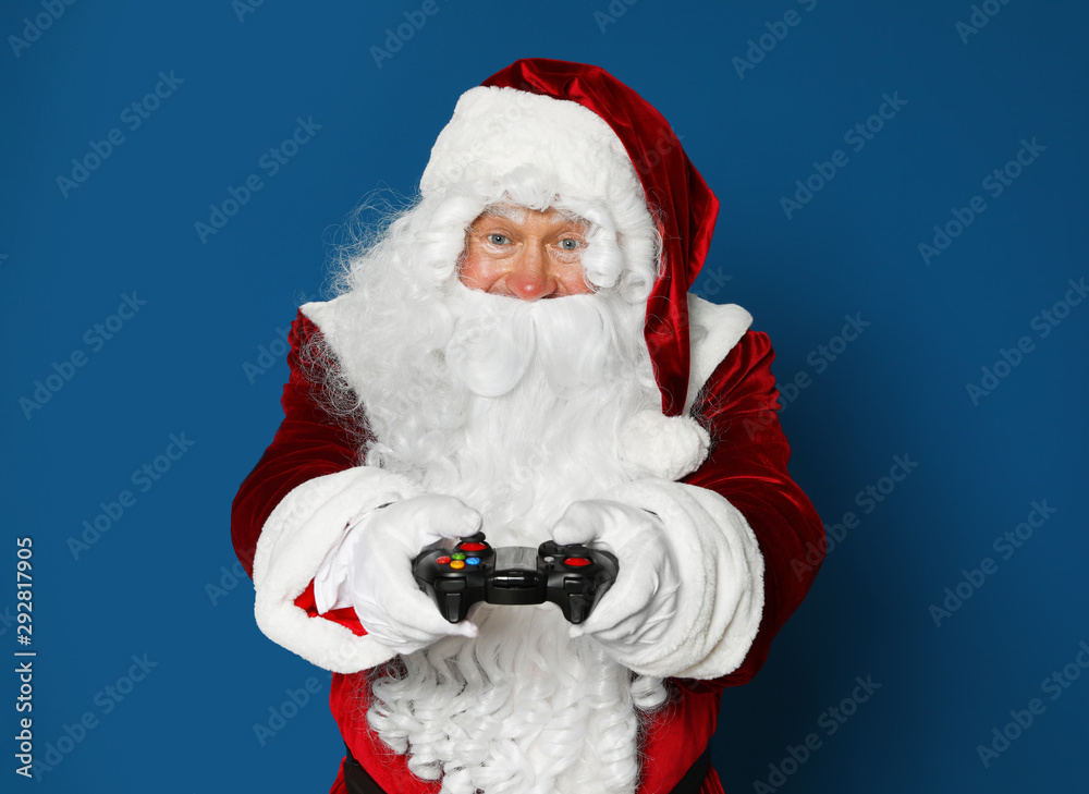 Authentic Santa Claus with game controller on blue background Authentic Santa Claus with game controller on blue background