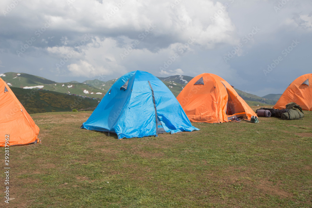 A multi-colored tents is set on a beautiful lawn in the mountains, the concept of a relaxed