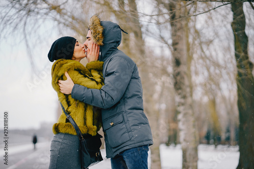 happy couple kissing and walking through the park on a sunny winter day