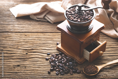 coffe bean with grinder and coffee in wooden spoon on wood table in morning light. photo