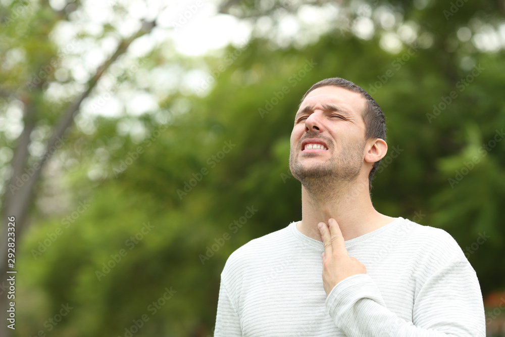 Man suffering throat ache complaining in a park Man suffering throat ache complaining in a park