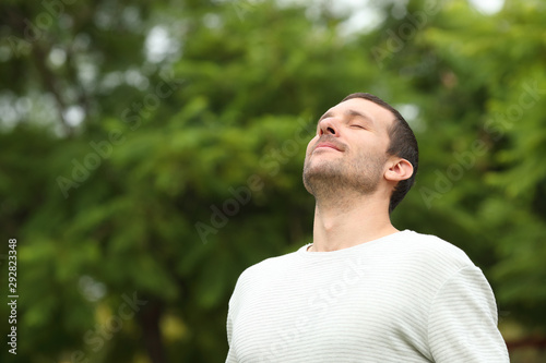 Relaxed adult man breathing fresh air in a forest