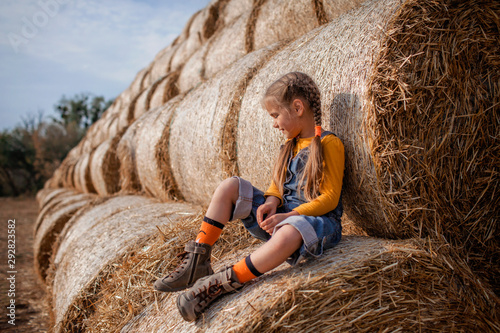 Slika na platnu Cute girl having fun on rolls of hay bales in field