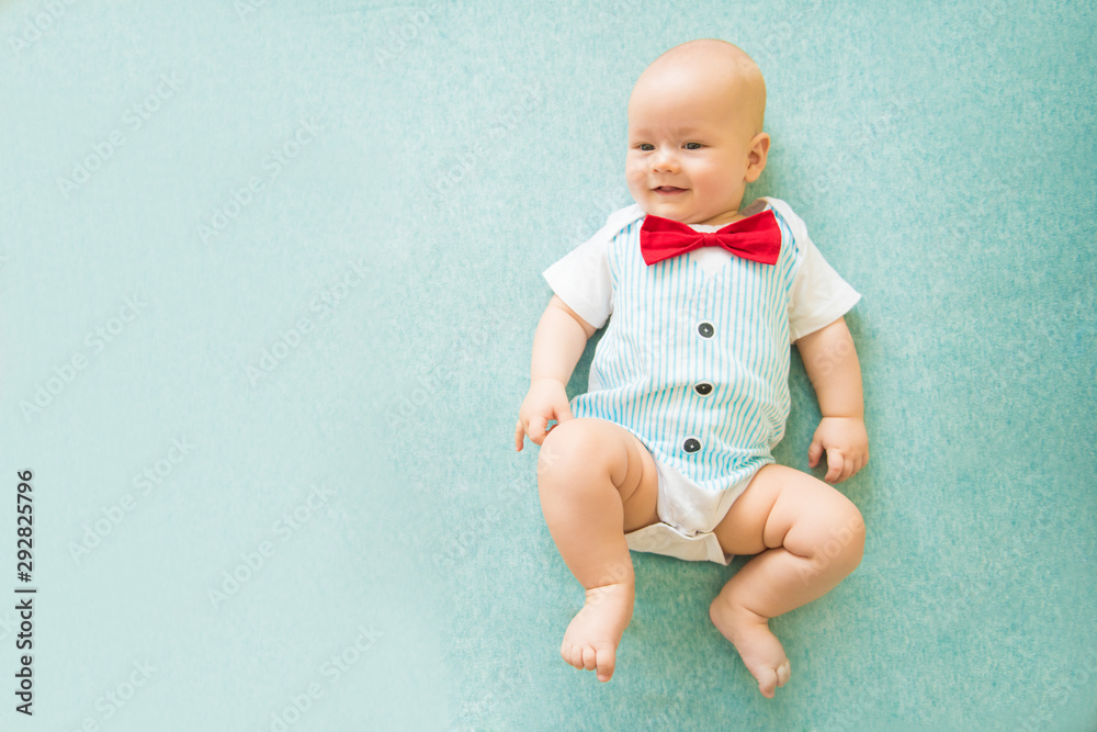 Calm curious baby lying on blue background, looking at camera, top view Calm curious baby lying on blue background, looking at camera, top view