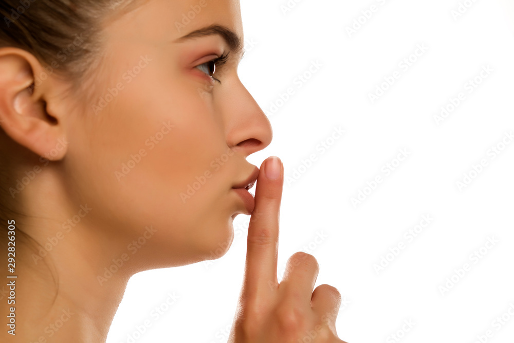 Young woman with finger on her lips on white background Young woman with finger on her lips on white background