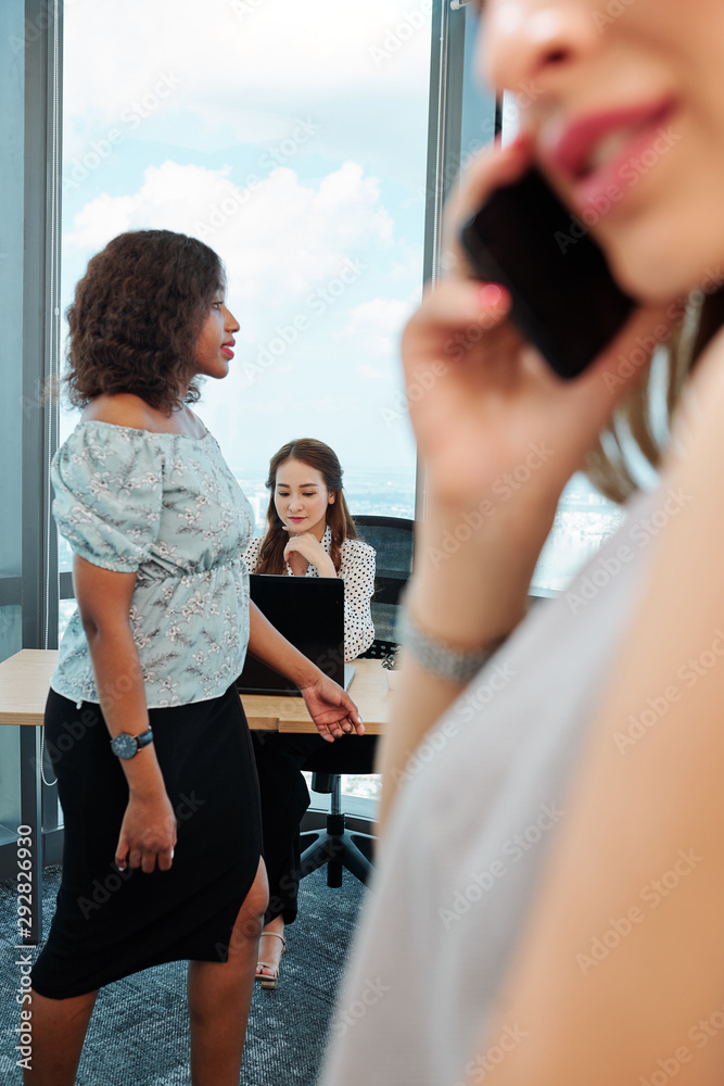 custom made wallpaper toronto digitalSerious businesswoman reading document on laptop when one of her coworkers walking by and another talking on phone with client