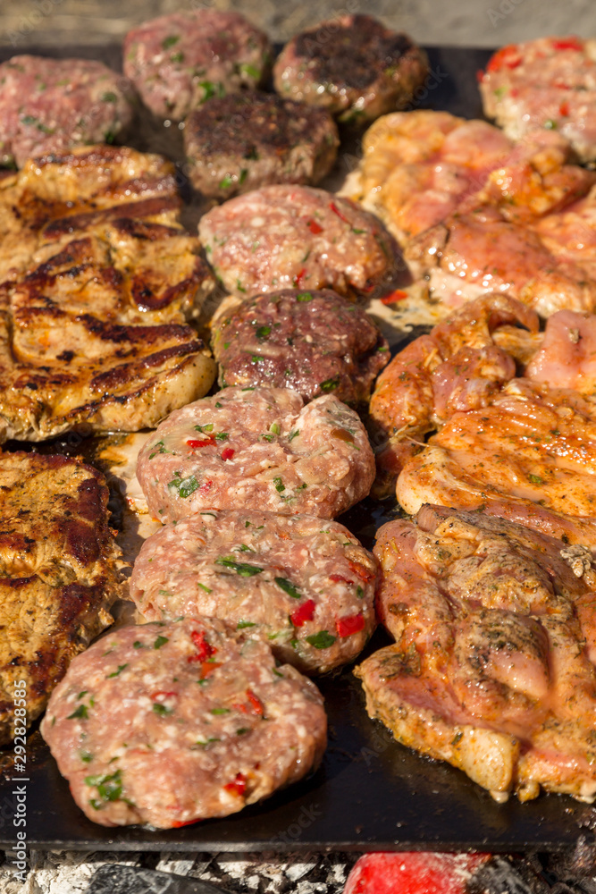 Meat grilled pork with vegetables. Meat balls and steak during grilling. Close up.