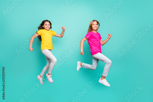 Full length body size photo of two cheerful people girls running towards something because of sales and discounts while isolated with teal background