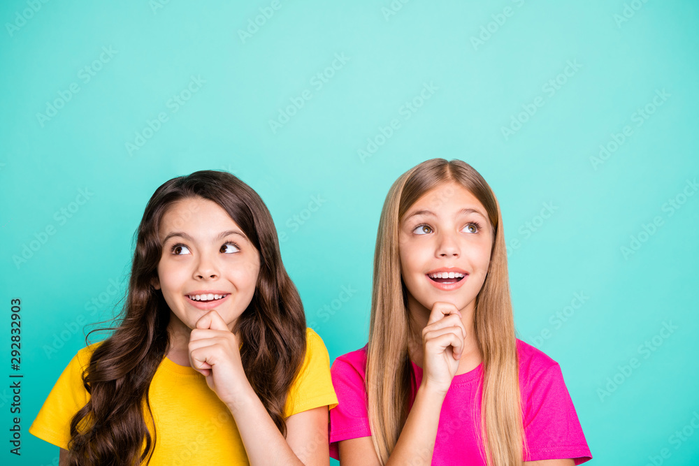 Photo of two cute nice good girls seeming cunning and sly pondering over something while isolated with teal background Photo of two cute nice good girls seeming cunning and sly pondering over something while isolated with teal background