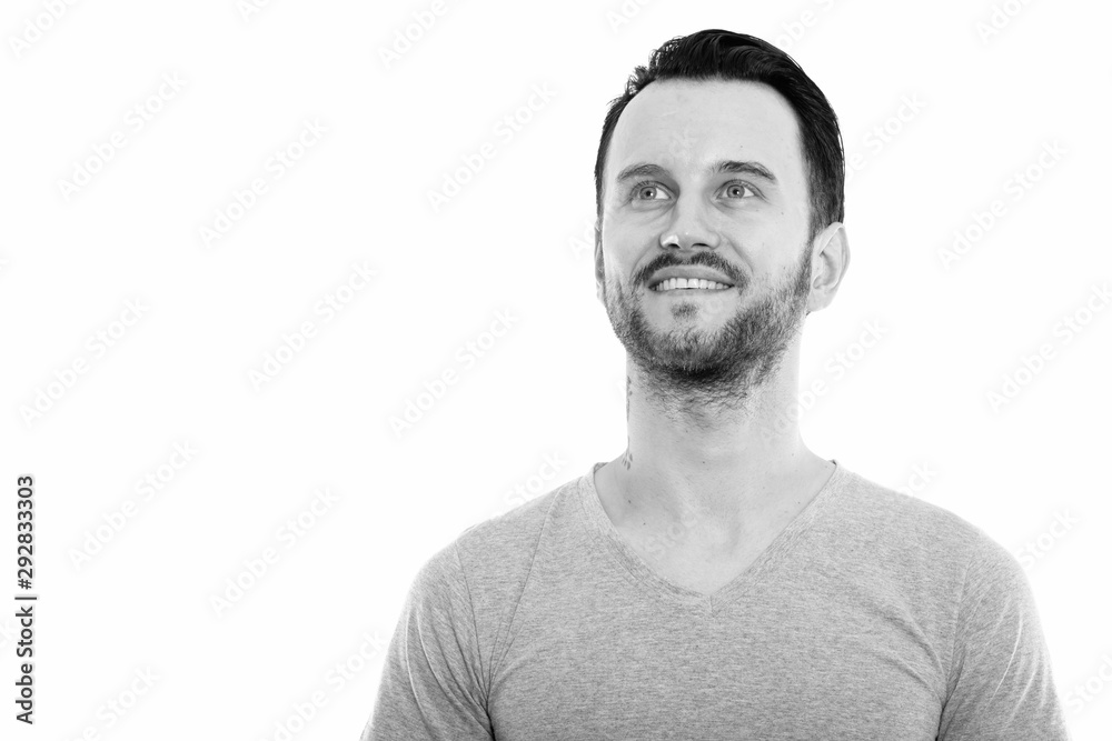 Studio shot of happy young man smiling and thinking while looking up Studio shot of happy young man smiling and thinking while looking up