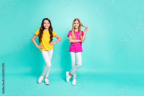 Full length body size photo of two future model stars posing to be photographed while isolated with teal background