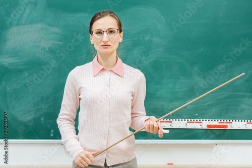 strict teacher standing in front of blackboard in class