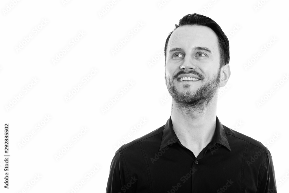 Studio shot of happy young man smiling and thinking while looking up Studio shot of happy young man smiling and thinking while looking up