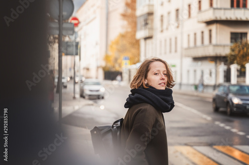 Young beautiful happy girl woman in a coat and scarf on a sunny autumn street