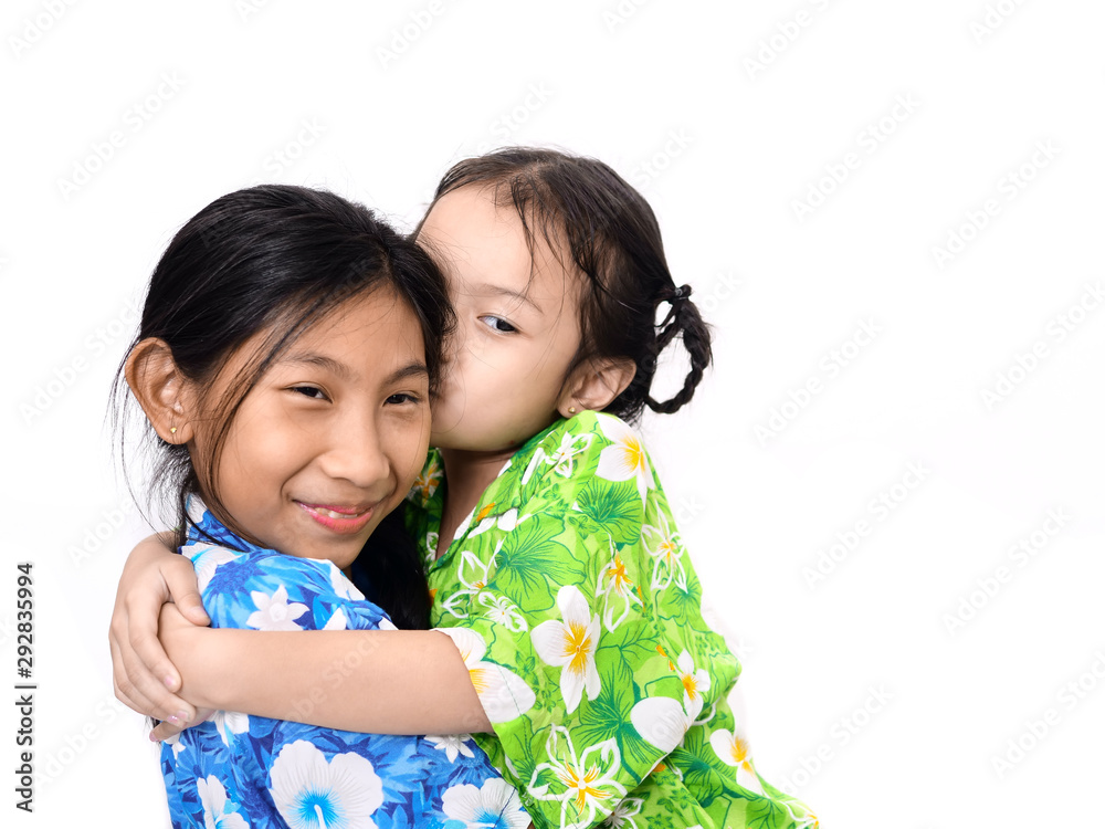 Happy Asian girl picking up her younger sister on white. Little girl kissing her sister. Happy Asian girl picking up her younger sister on white. Little girl kissing her sister.