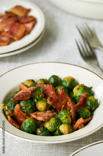 Fried brussels sprouts with bacon in a white bowl