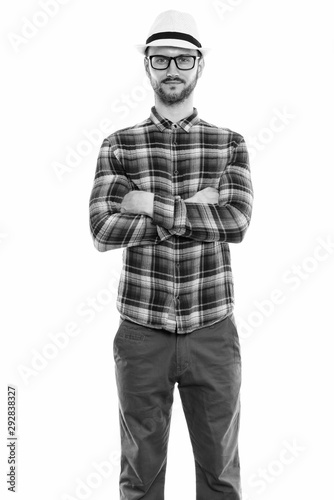 Studio shot of young man standing with arms crossed
