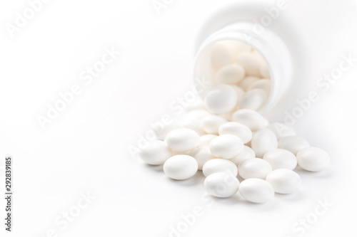 Pill bottle spilling medical pills onto surface isolated on a white background.