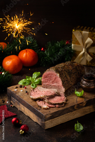 Juicy roast beef with spices sliced on cutting Board, delicious meat, traditional food. Christmas holidays, new year, menu on dark background