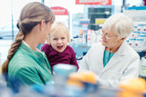 Friendly pharmacist, mother and child having fun in pharmacy