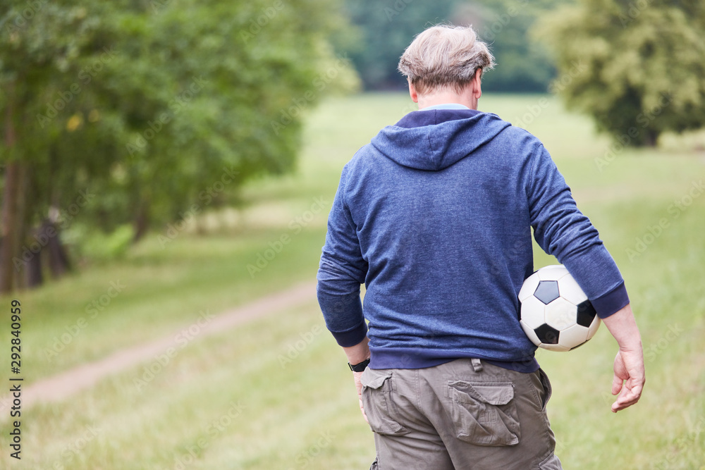 Naklejka premium Senior Mann mit einem Fußball unter dem Arm