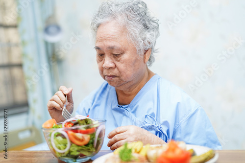Asian senior or elderly old lady woman patient eating breakfast healthy food with hope and happy while sitting and hungry on bed in hospital..