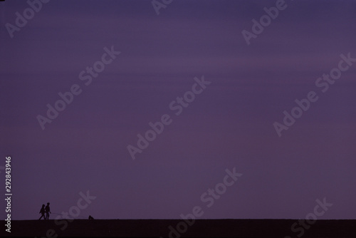 silhouette of man and woman walk on sunset