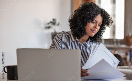 Canvas Print Smiling young female entrepreneur going over paperwork at home