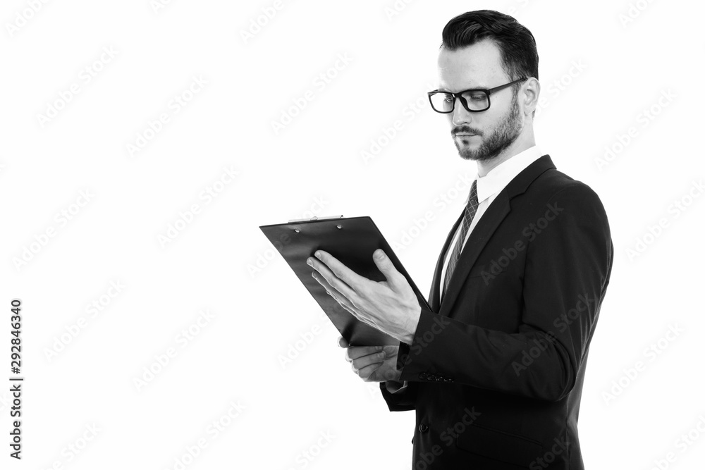Studio shot of young businessman reading on clipboard