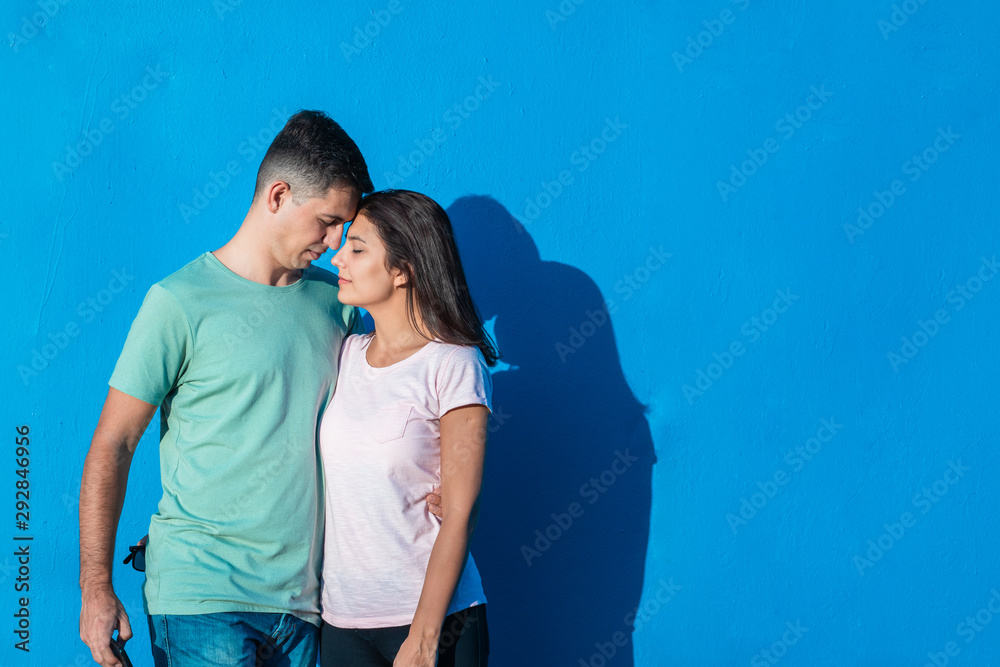 Naklejka premium Young couple smiling standing together isolated on blue background. People and emotions concept with copy space.
