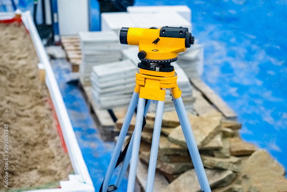 Preparation for construction. Yellow theodolite on the background of the construction. Geodesy. Theodolite on a tripod. Geodetic measurement instruments. Measuring device for determining angles.