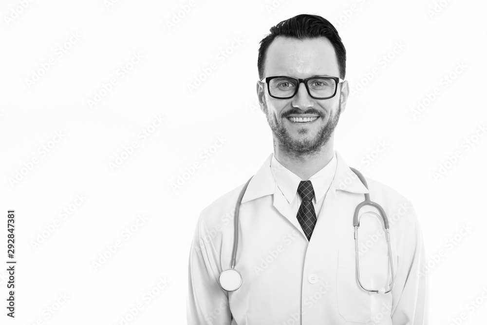Studio shot of happy young man doctor smiling while wearing eyeglasses Studio shot of happy young man doctor smiling while wearing eyeglasses