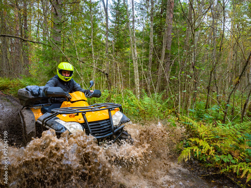 A man in a helmet riding an ATV. All-terrain vehicle. Extreme trip through the forest. Sale of ATVs.Outdoor activity.Off-road.A man passes through a swampy part of the forest. A man drives a Quad bike