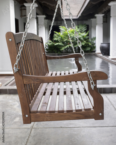 The detail of brown wood swing in the backyard.
