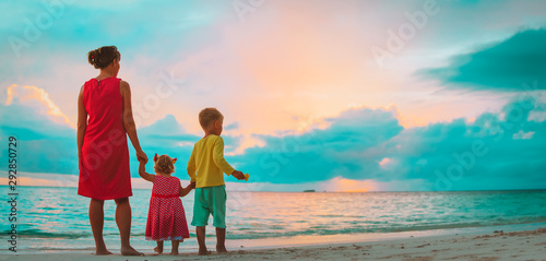 mother with little son and daughter looking at sunset beach