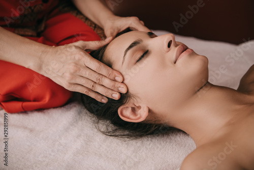 cropped view of masseur doing face massage to woman in spa salon