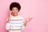Photo of pretty excited dark skin lady holding telephone talking with best friend wear white striped pullover isolated pastel pink color background