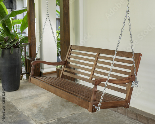 The brown wood swing in the backyard.