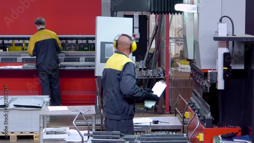 Worker operator bending metal sheet process by sheet bending machine for bus manufactuing part, steel folding with machine