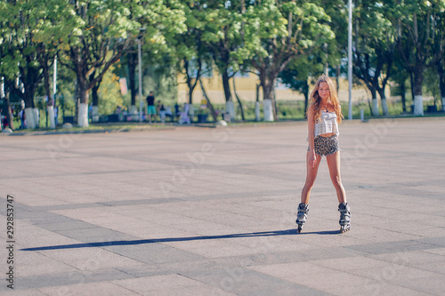 young woman rides in the park in roller skates