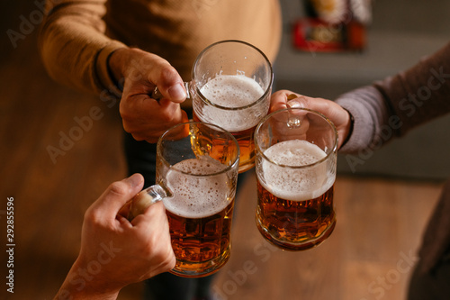 Slika na platnu Group of happy friends drinking and toasting beer at bar
