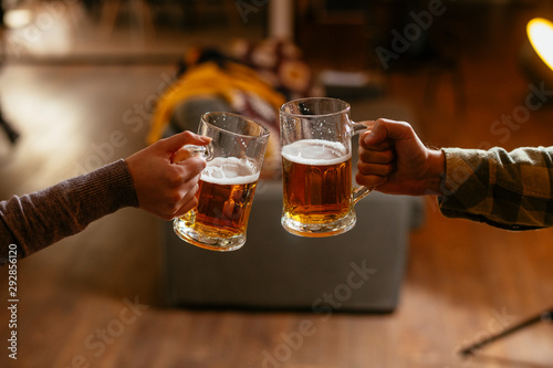 Canvas Print Close-up of two people toasting with beer.