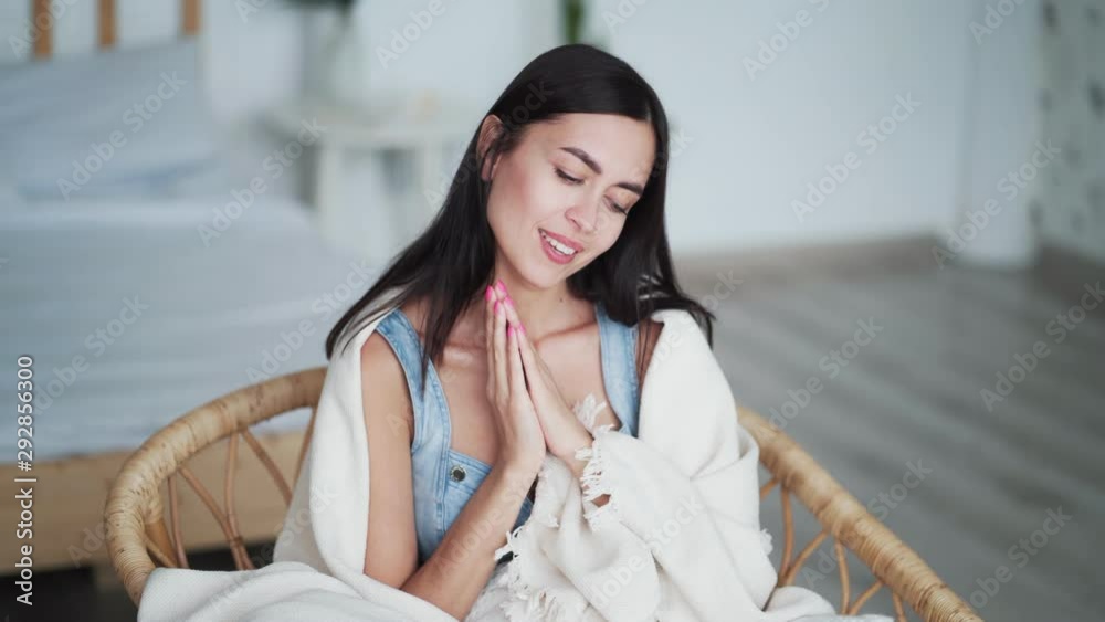 Beautiful young woman sitting in chair wrapped in plaid and yawns Beautiful young woman sitting in chair wrapped in plaid and yawns