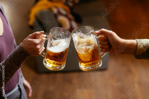 Close-up of two people toasting with beer.
