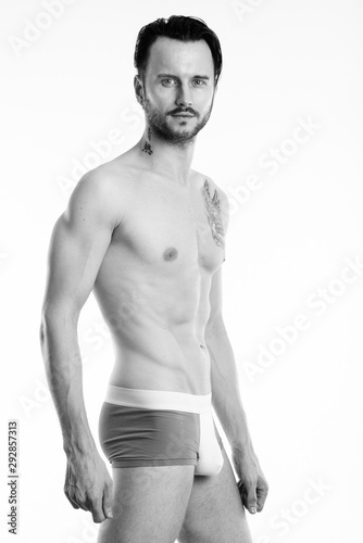 Studio shot of young shirtless man standing and posing