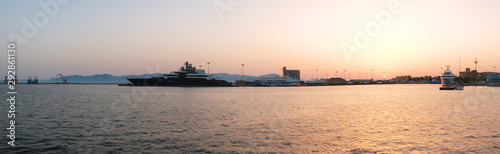 AUG 2019 seascape of port of Cagliari at sunset with big yacht and boat with container - Sardinia.
