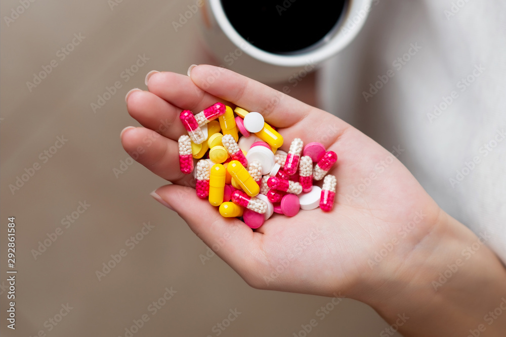 a palm full of pills and a cup of coffee is visible nearby a palm full of pills and a cup of coffee is visible nearby